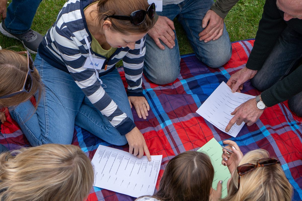 A group sitting on a picnic blanket reading and talking together