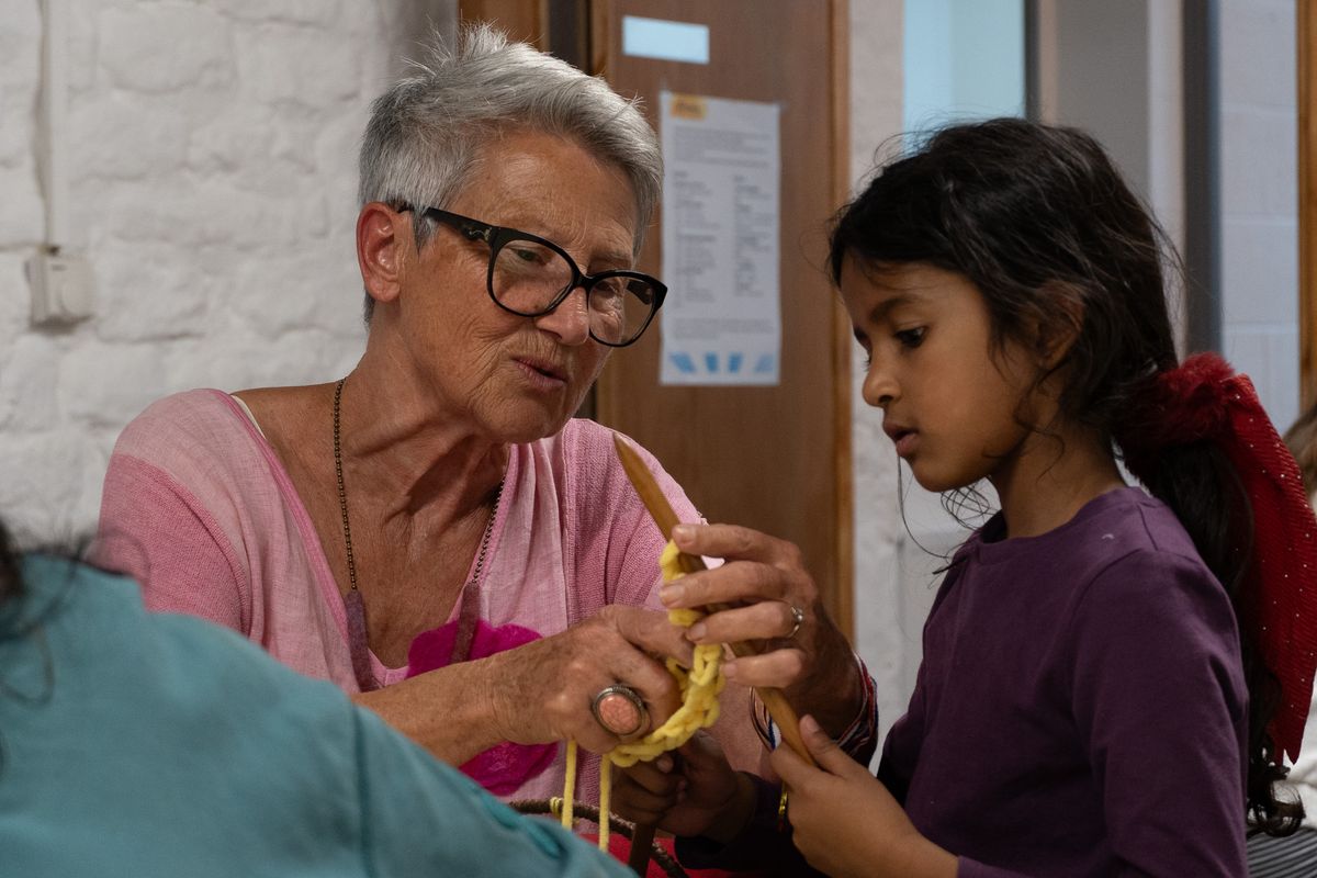 An older church member showing a young girl how to do a craft