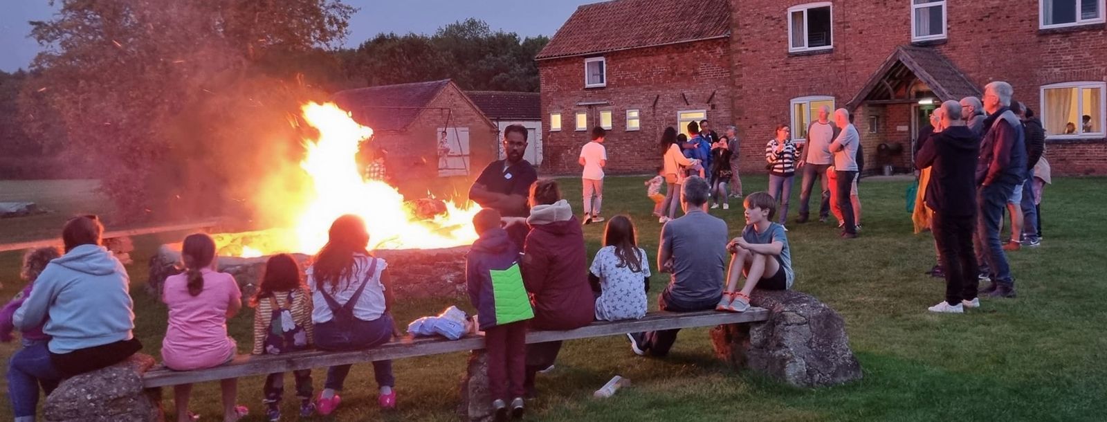 Families gathered round a bonfire at dusk on the Connect Weekend Away