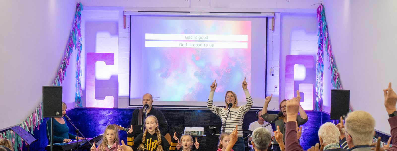 Children and adults worshipping with hands raised at the Connect Weekend Away